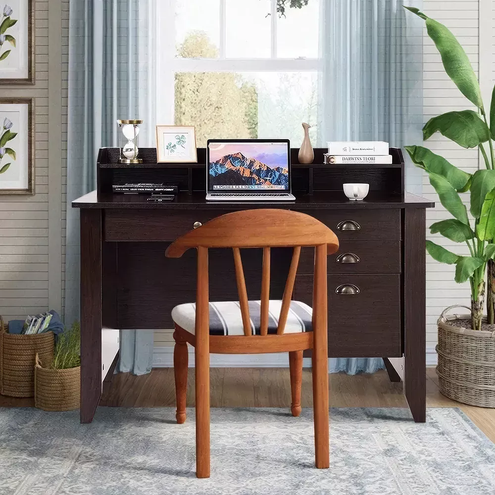 Home office setup featuring a dark wood desk with drawers, a wooden chair, laptop, and indoor plant near a window with natural light